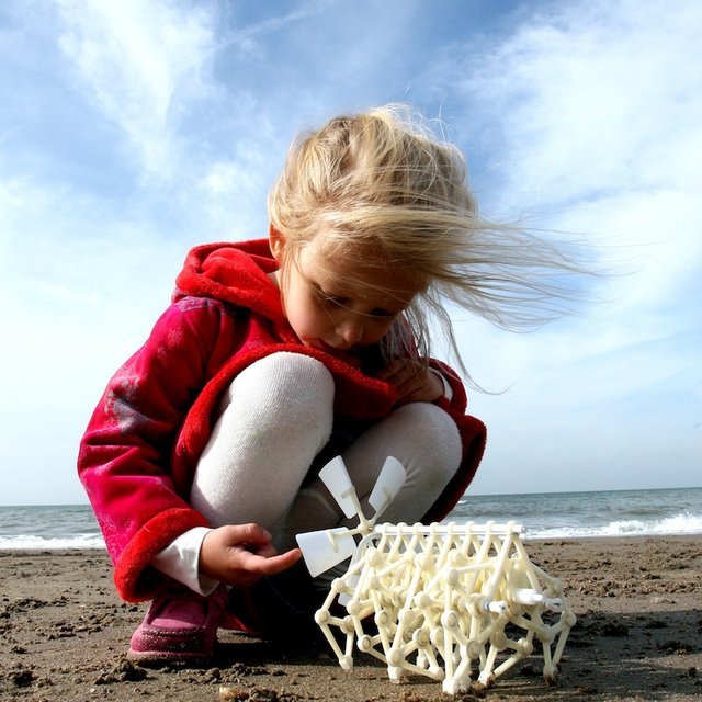 Child playing with a white sand sculpture on a beach