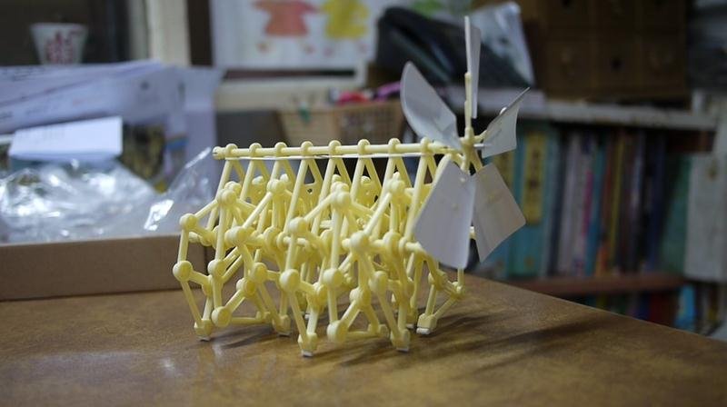 Yellow model of a bridge with a windmill on a wooden surface