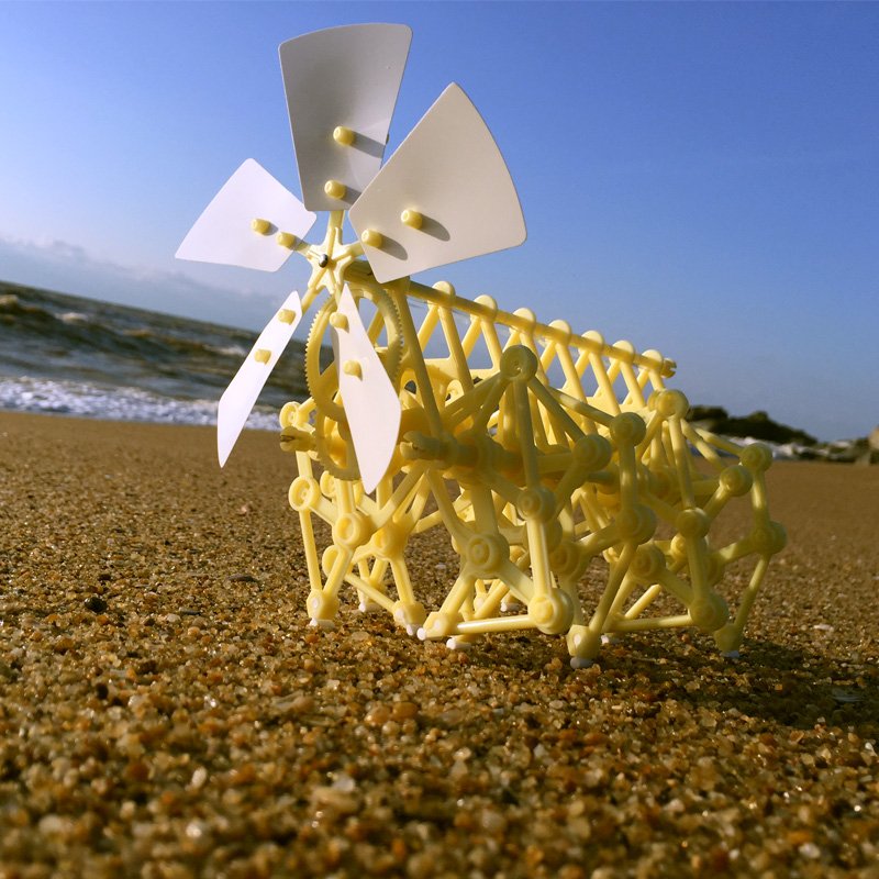 Yellow mechanical model with wind turbines on a sandy beach