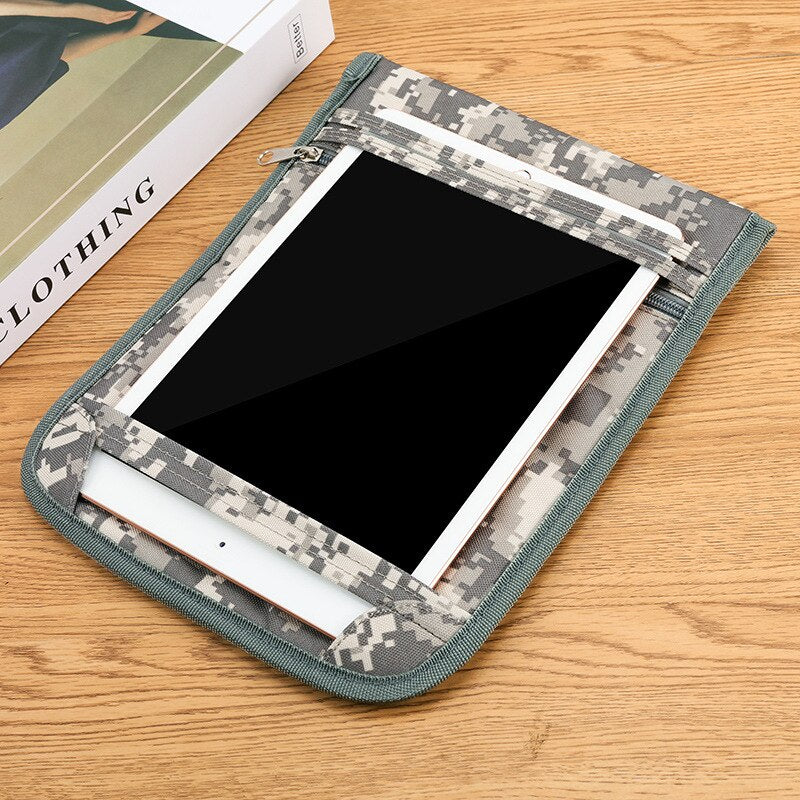 A tablet pouch in a gray and beige digital camouflage pattern, shown holding a tablet on a light wood tabletop next to a book.