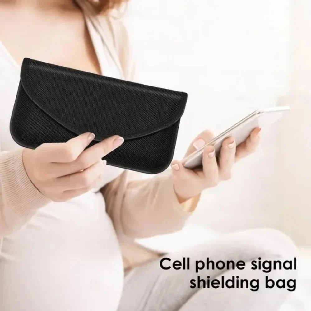 Person holding a smartphone and a black signal shielding bag