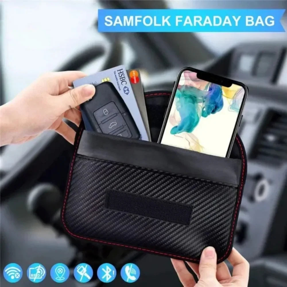 Black Faraday bag held by hands with phone and keys inside, car interior background