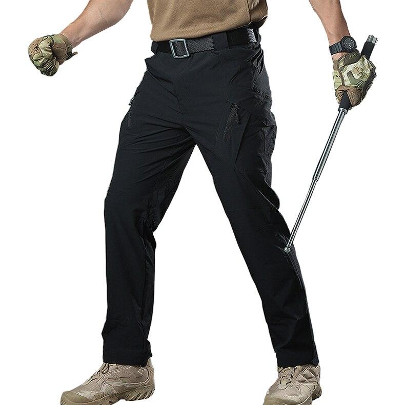 Person wearing black tactical pants with camouflage gloves and boots on a white background